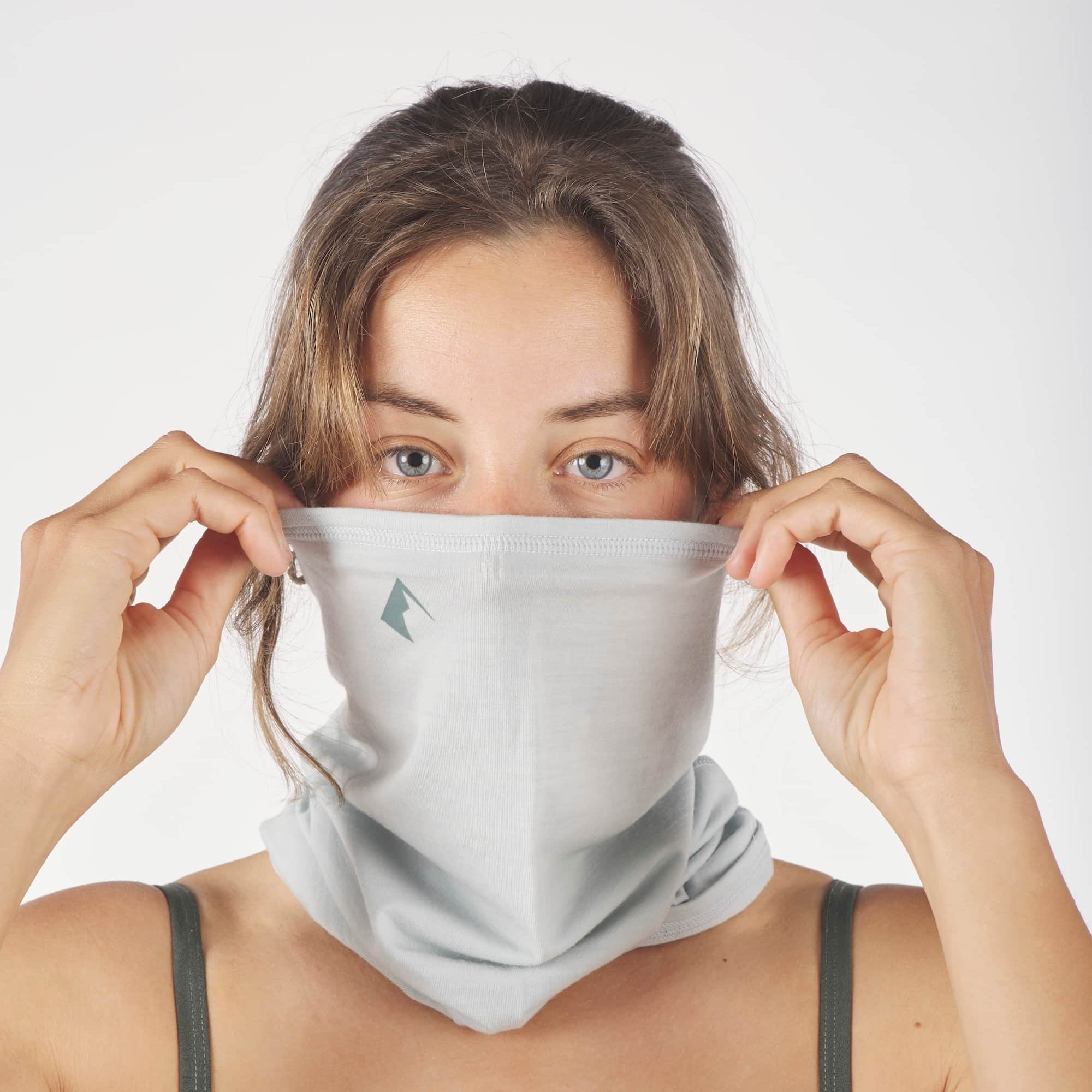 a woman pulling up her Sierra Merino Wool Neck Tube in Ice Flow