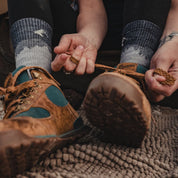 a woman putting hiking boots on over Minaret Hiking Socks