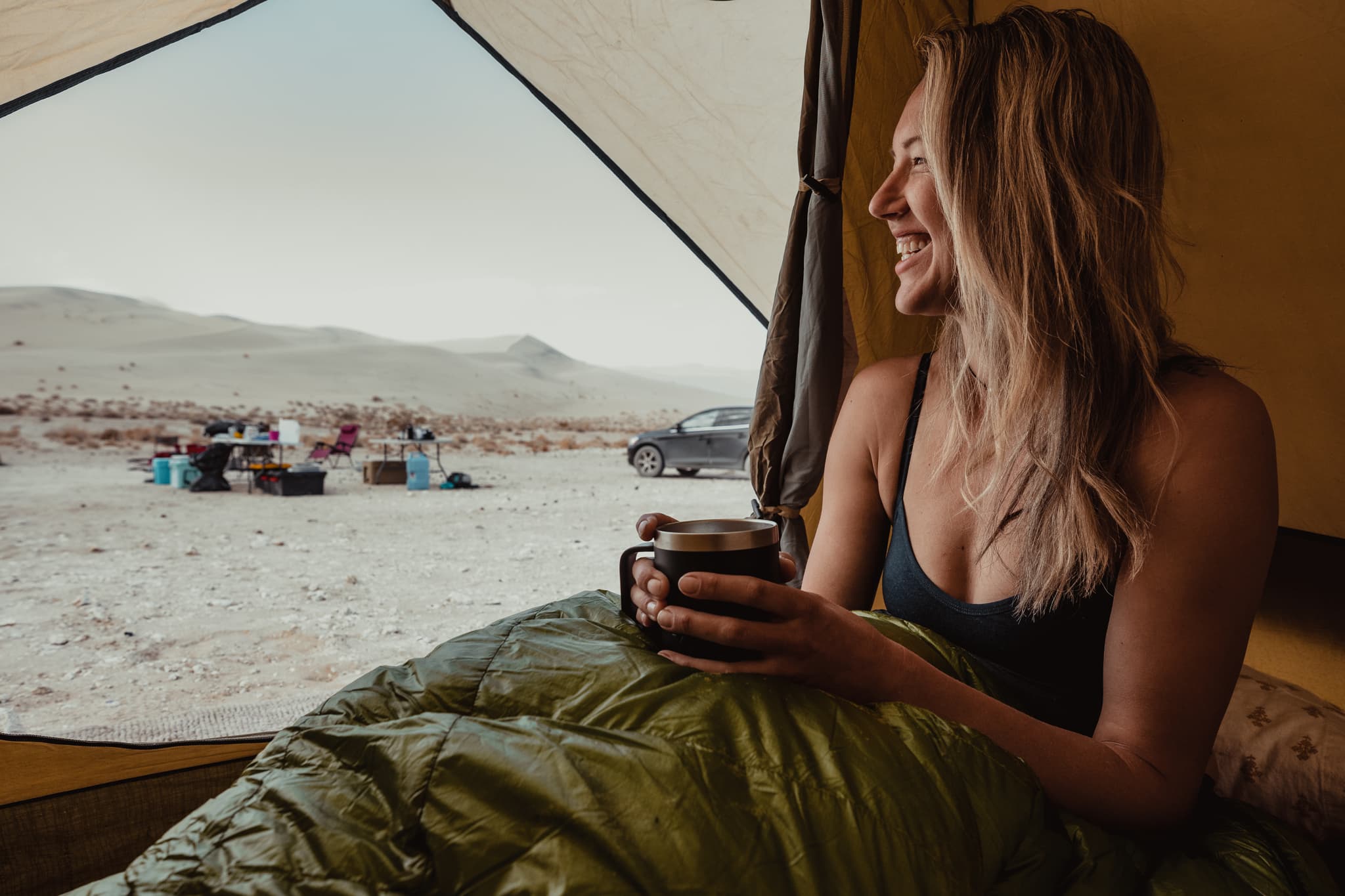 a woman smiles wearing a Merino bralette in a tent