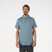 Man wearing a light blue polo shirt and dark pants on a white background