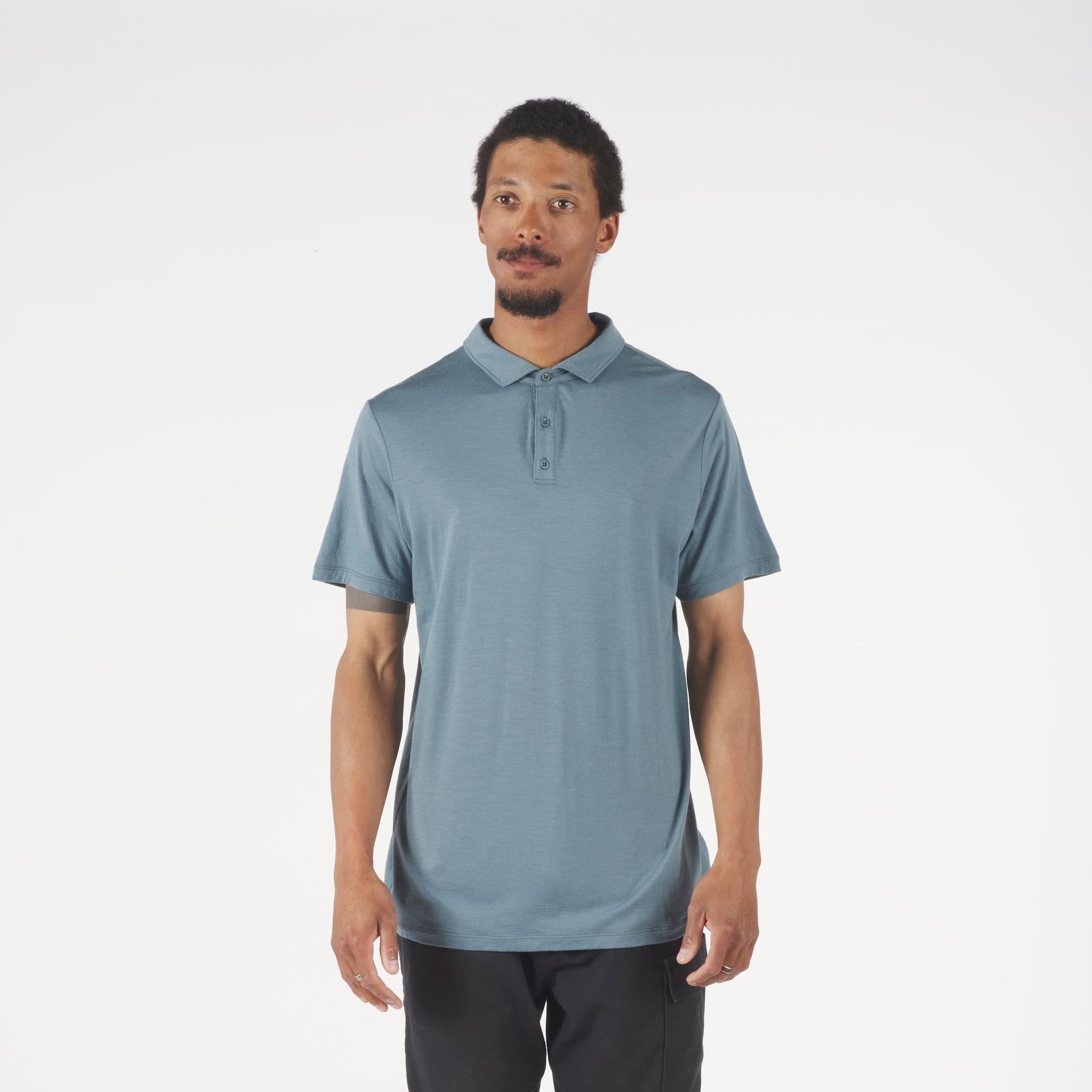 Man wearing a light blue polo shirt and dark pants on a white background