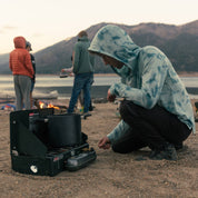 a man cooking a camp dinner in a Ridge Merino Solstice Sun Hoodie in tie-dye - photo by Carson Cox
