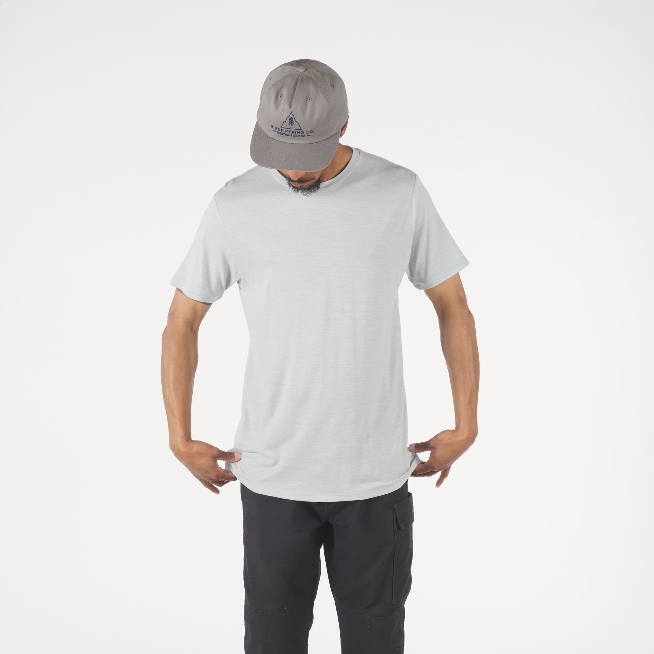 Person wearing a gray Journey Merino t-shirt, dark pants, and a cap on a white background