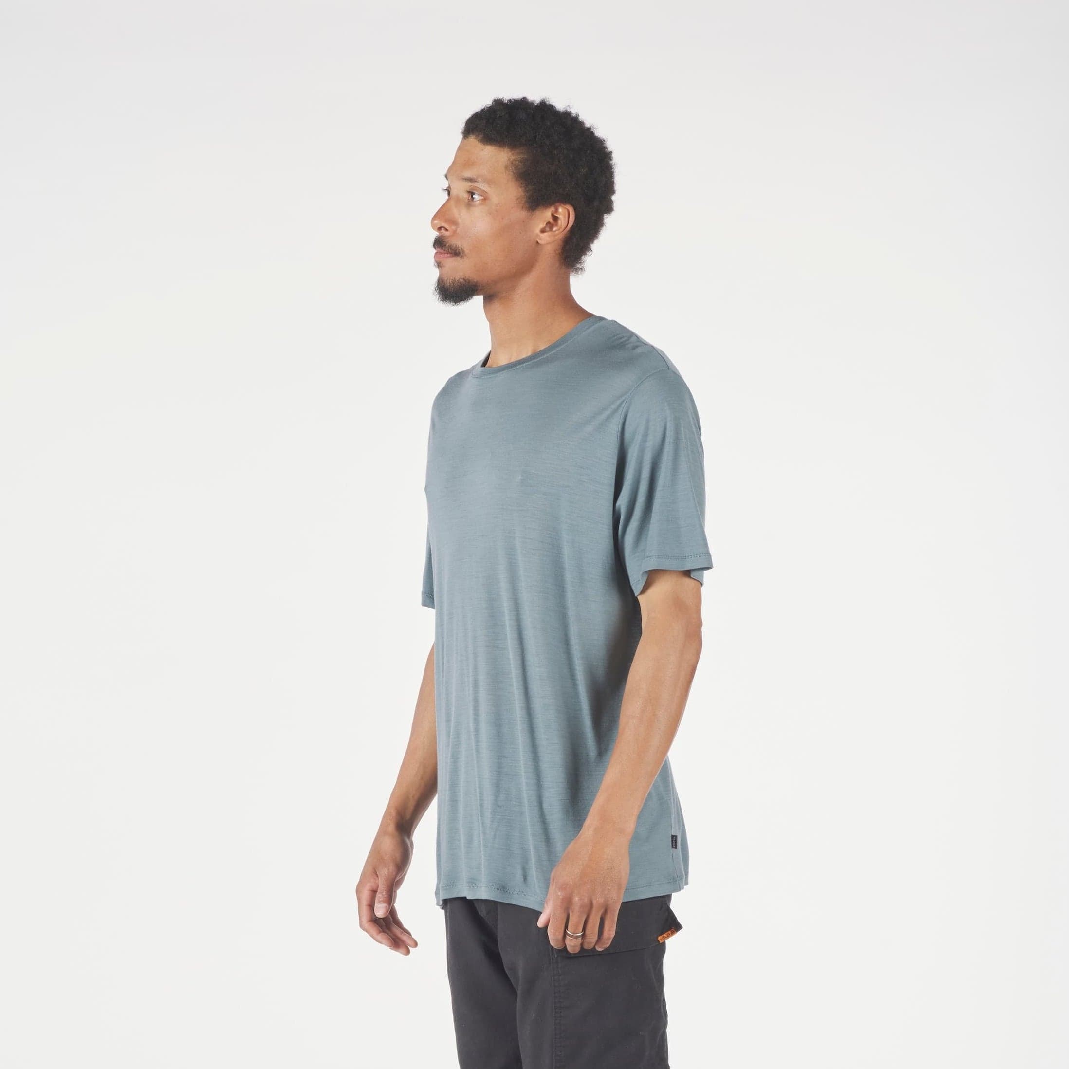 Man wearing a light blue t-shirt and dark pants on a white background