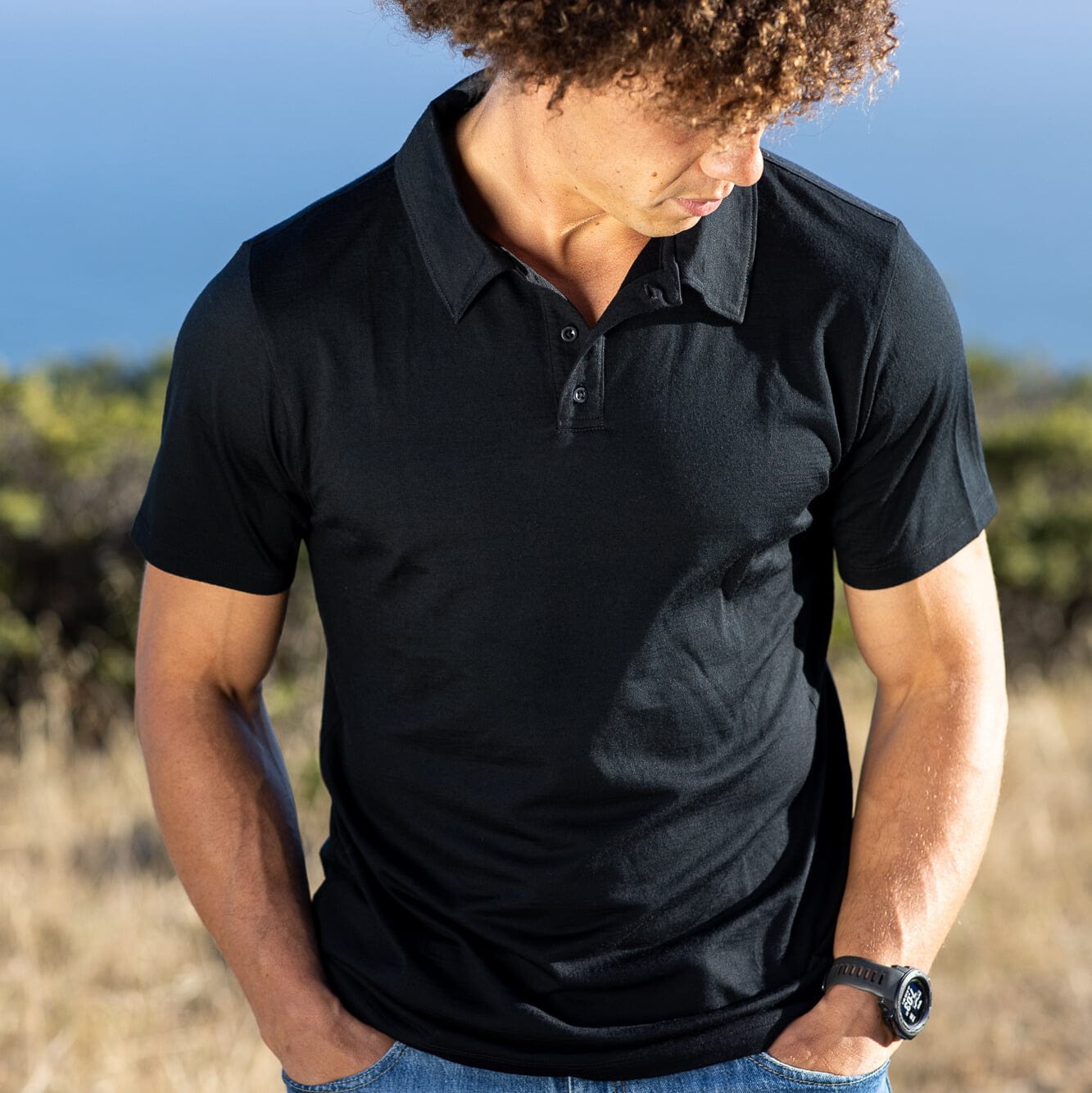 a man wearing a Journey Polo Shirt in black in a field