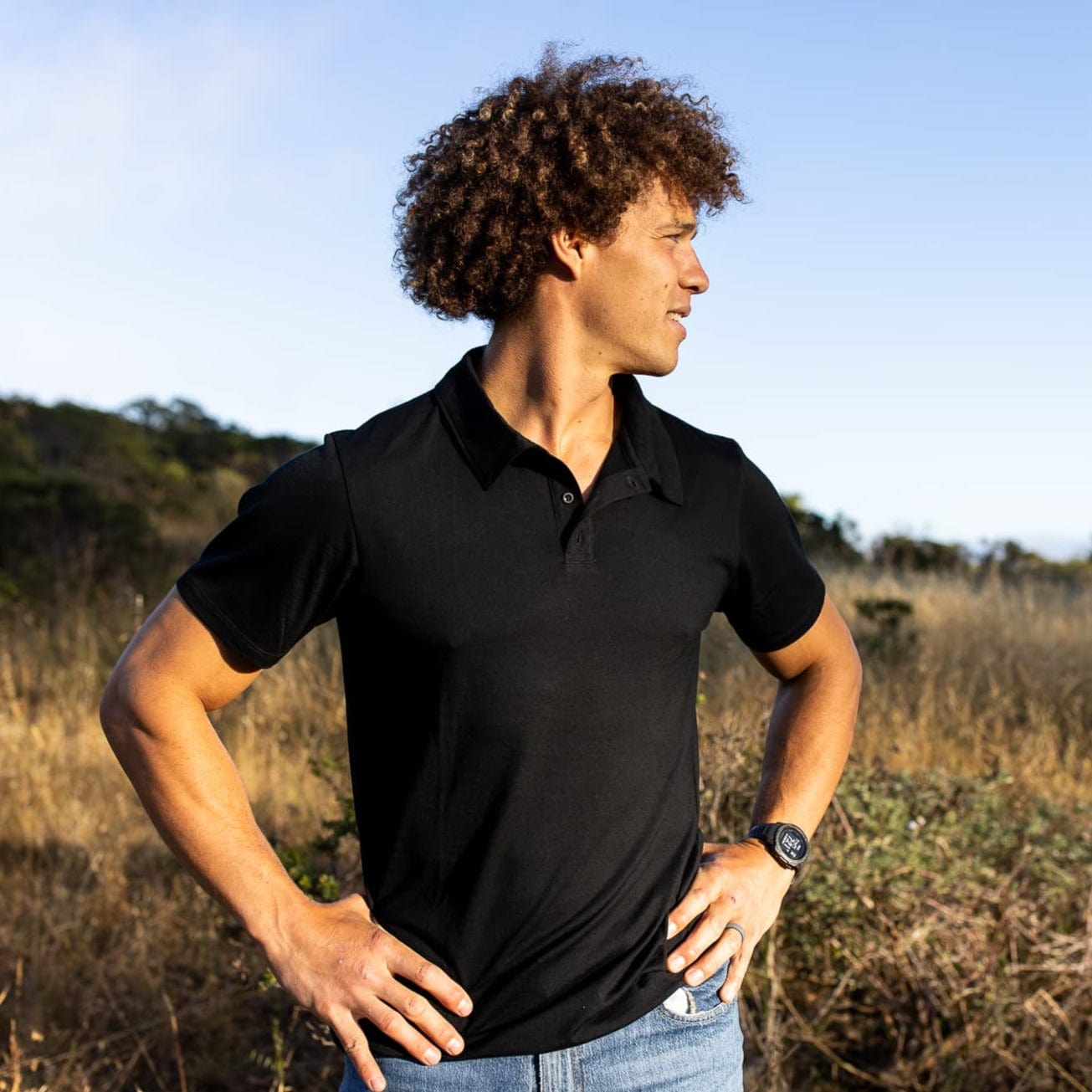 a man wearing a Journey Polo Shirt in black in a field