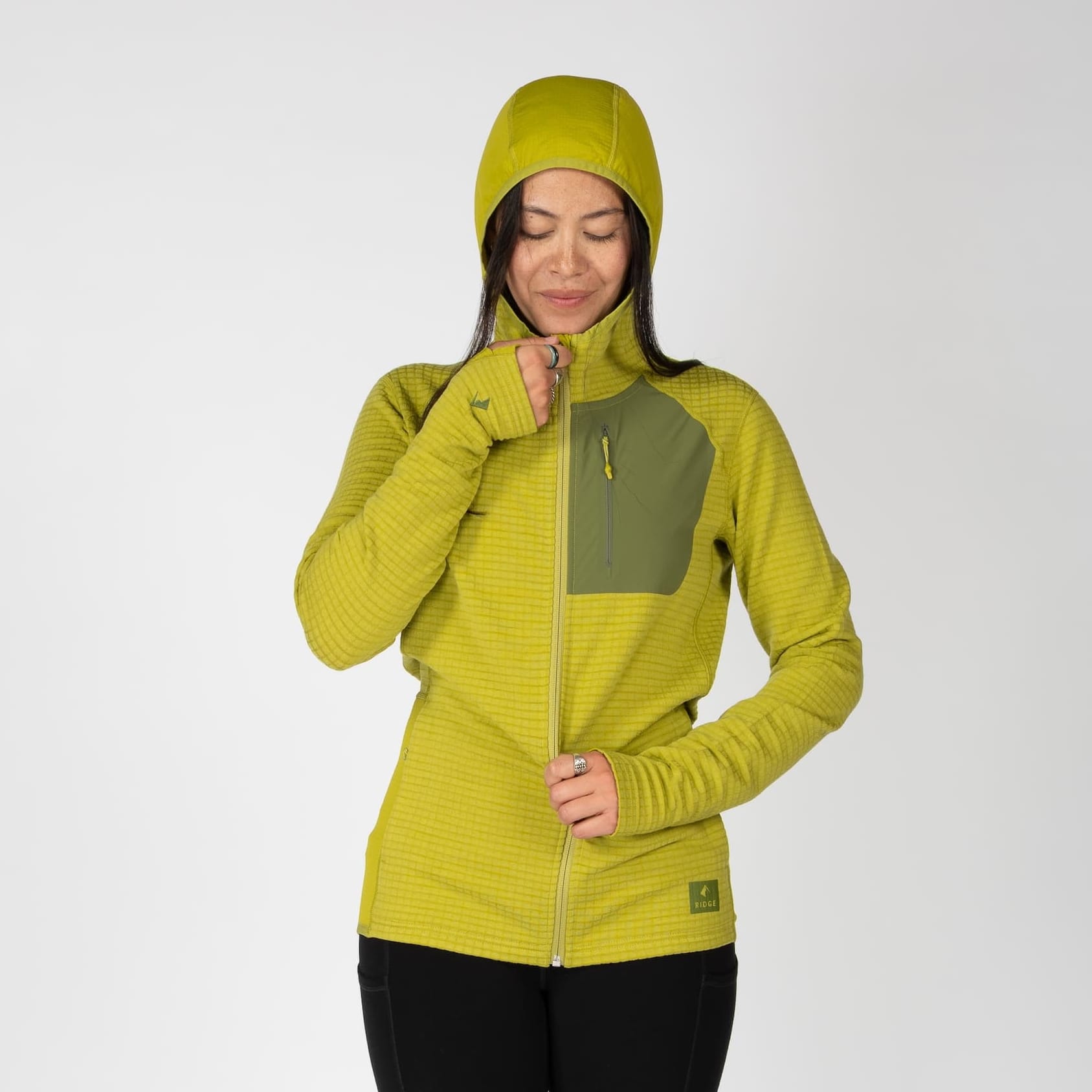 a woman zipping up a Cloudripper Grid Fleece Full Zip in Golden Lime