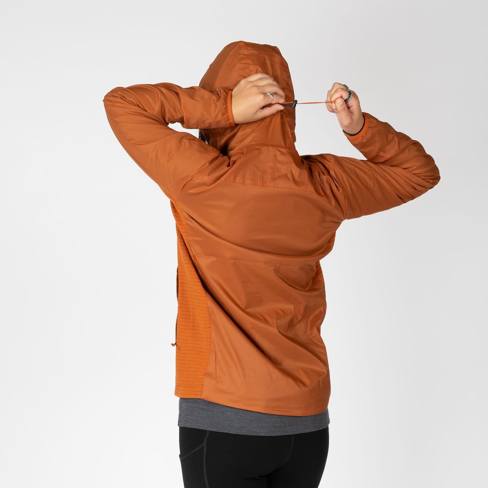 a woman showing the hood cinch on an orange Alpha Wool Insulated jacket