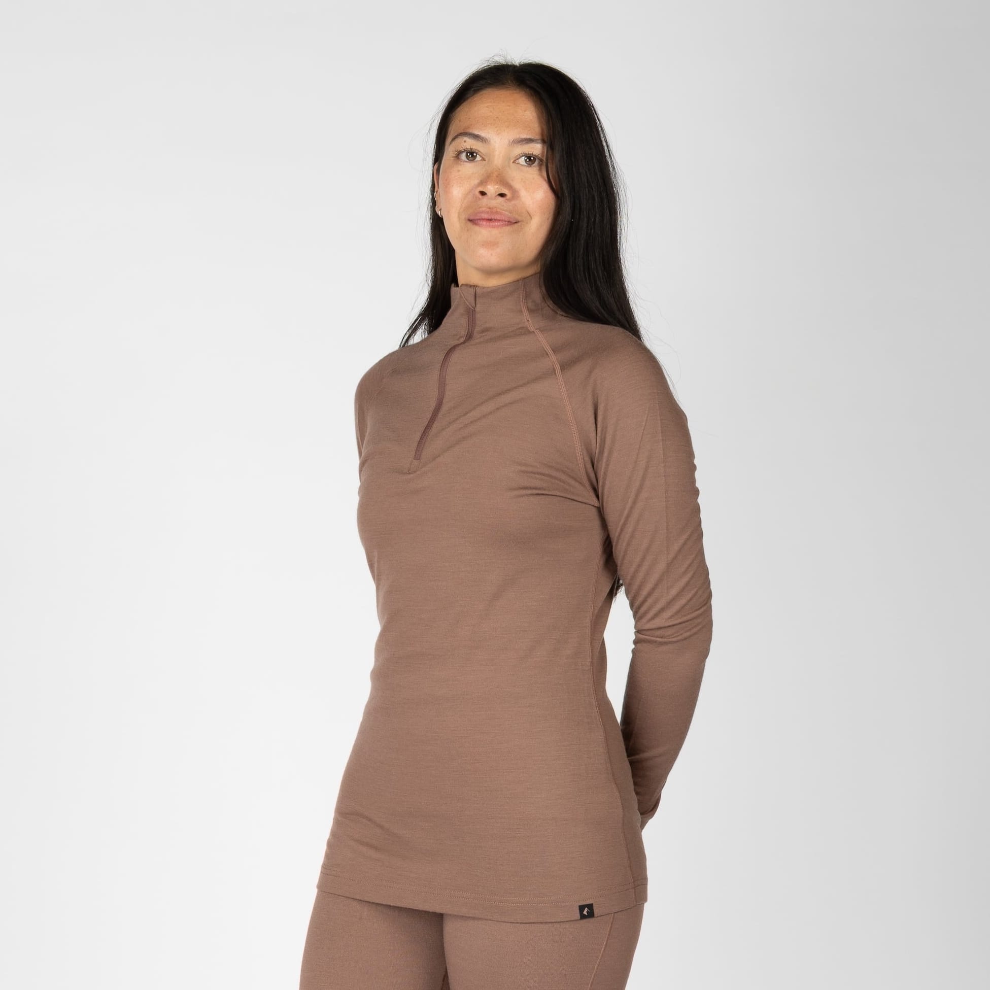 a woman wearing a 1/4 zip base layer top in Nutmeg with matching bottoms