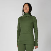 a woman wearing an Aspect Merino High Neck Base Layer Top in Fern with matching bottoms