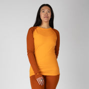a woman wearing a Sun Orange and Cinnamon Aspect Base Layer Crew Top with matching bottoms