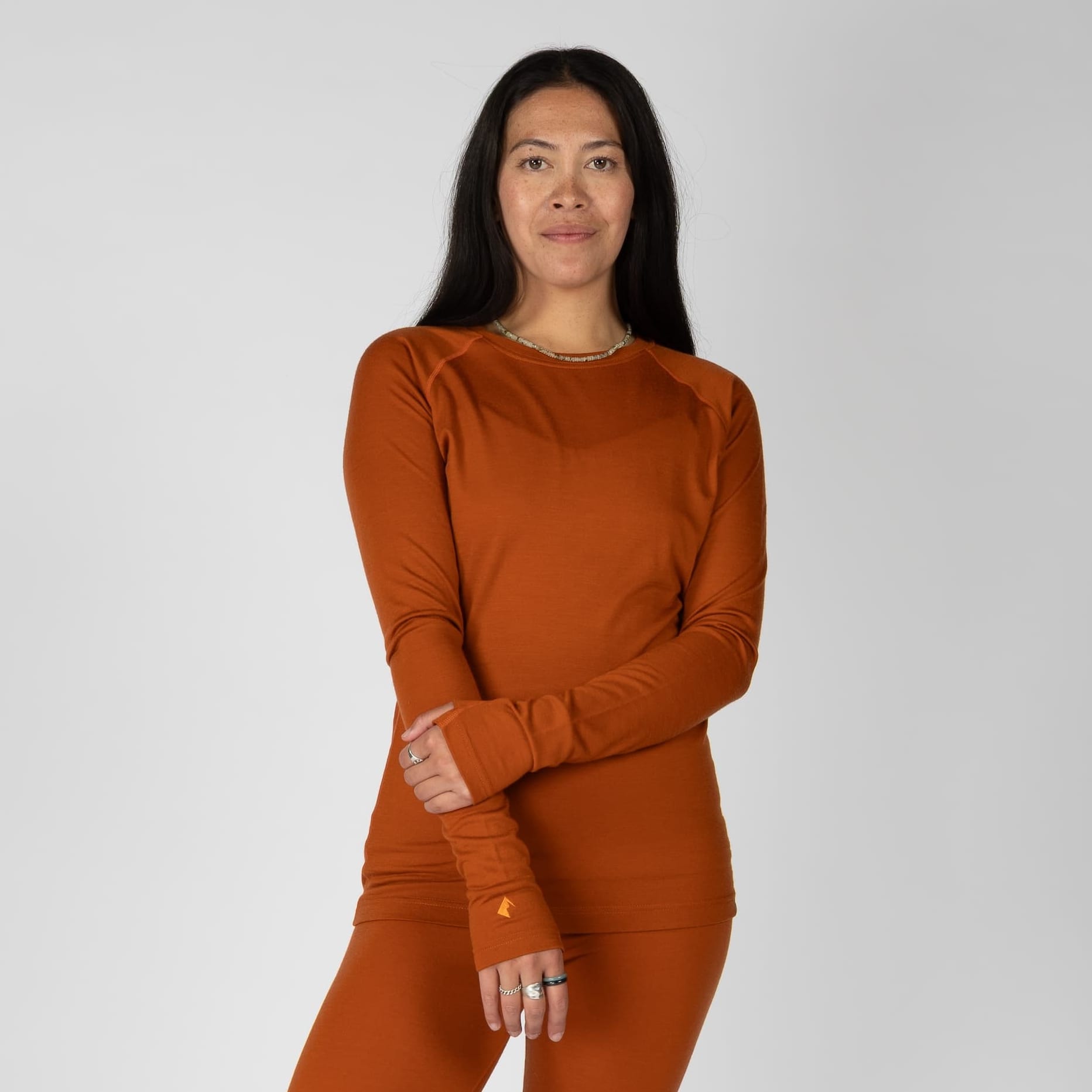 a woman wearing a Cinnamon Aspect Base Layer Crew Top with matching bottoms