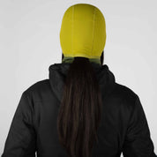 a woman wearing a Cloudripper Balaclava in Fern / Golden Lime from the back with her ponytail through the ponytail hole