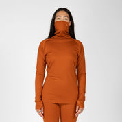 a woman wearing an Aspect Merino High Neck Base Layer Top in Cinnamon with matching bottoms