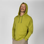 a man wearing a Golden Lime Solstice Merino Sun Hoodie with tan hiking pants