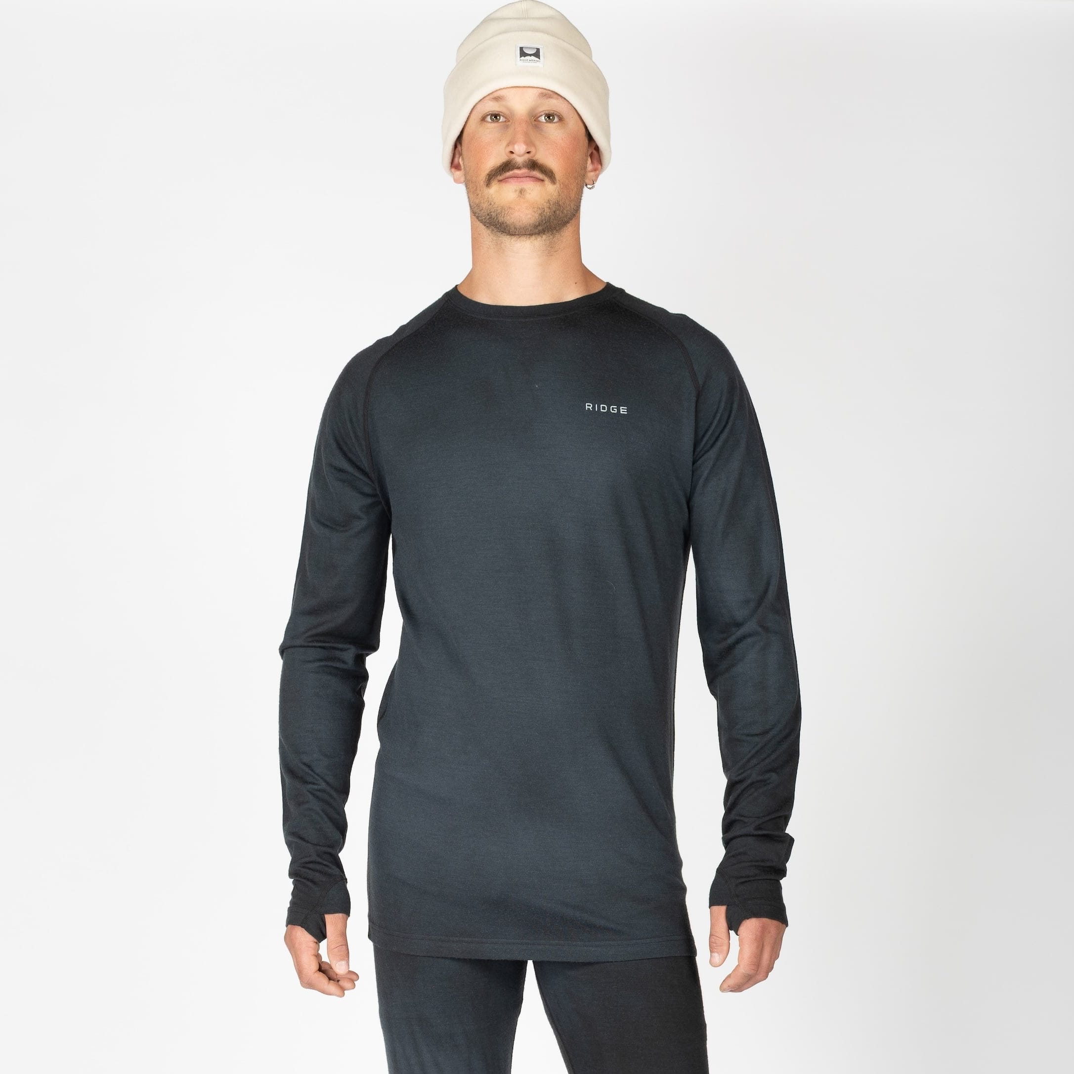 a man wearing an Aspect Base Layer Top in Black Garment Dye with a Ridge logo on the chest