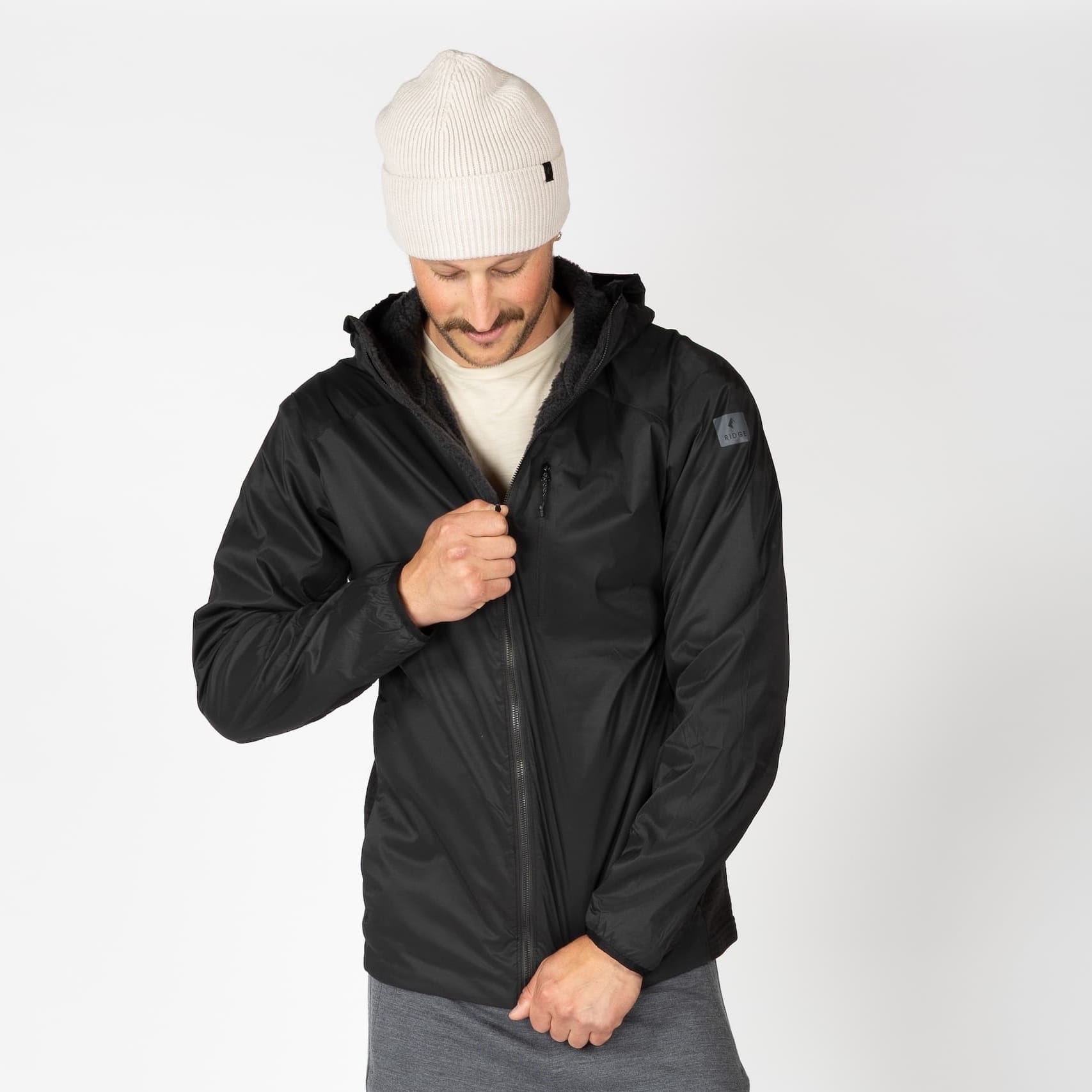 a man wearing a black Alpha Wool Insulated Jacket with a white beanie
