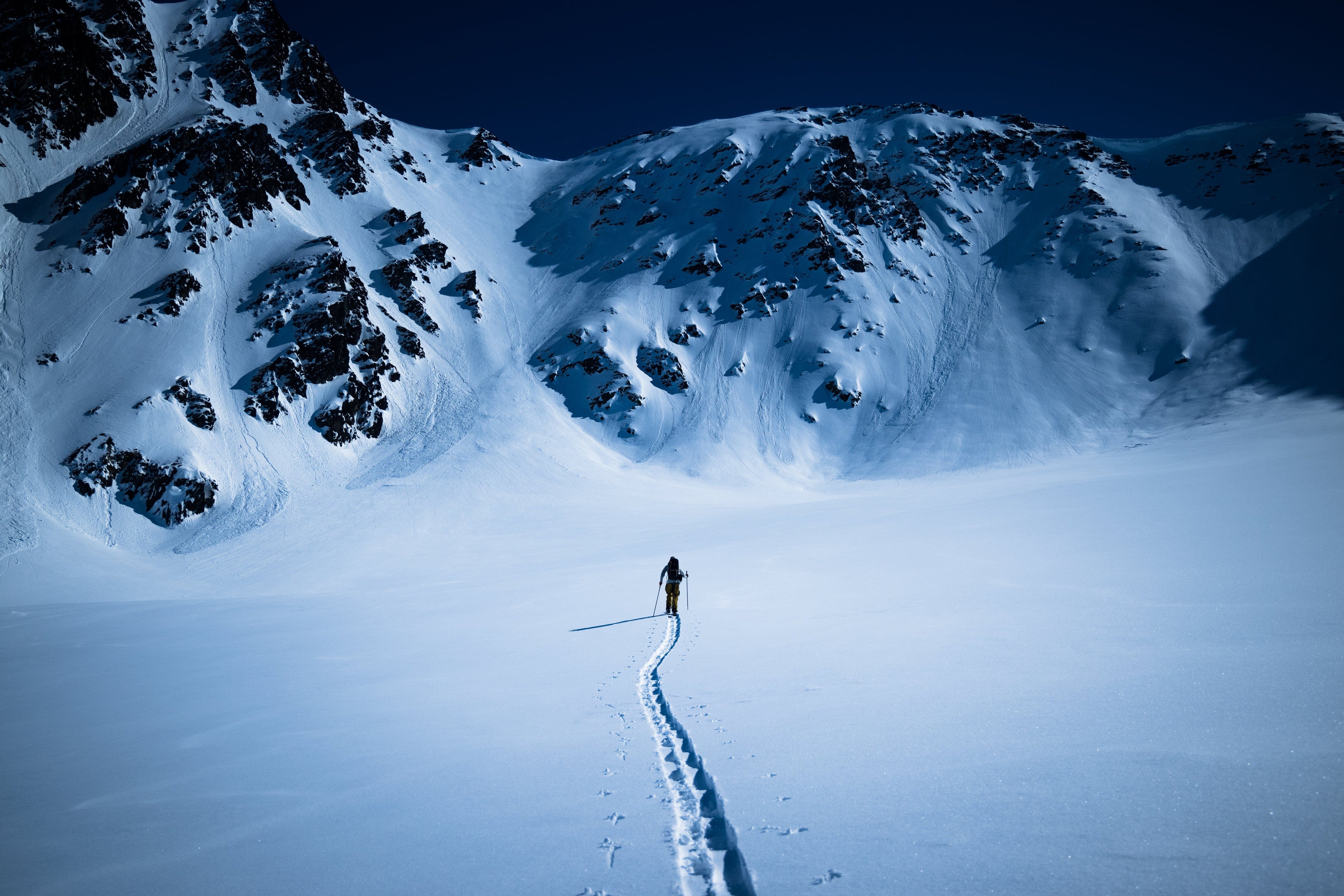 snowboarder makes a skin track toward mountains in the distance
