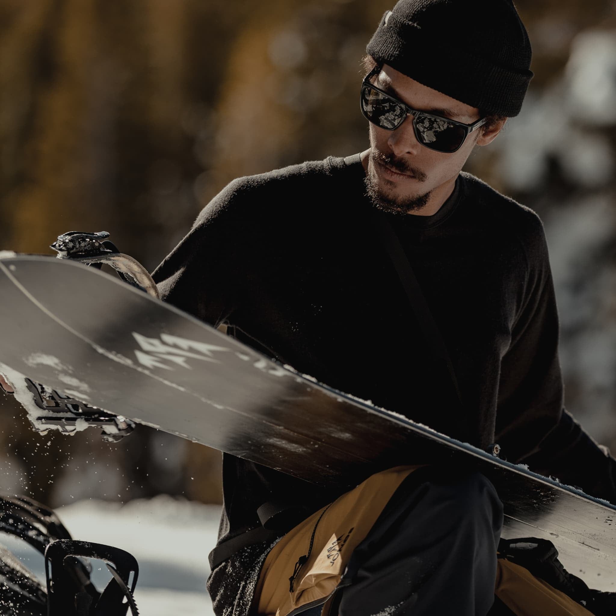 a snowboarder sets up his snowboard for the backcountry descent