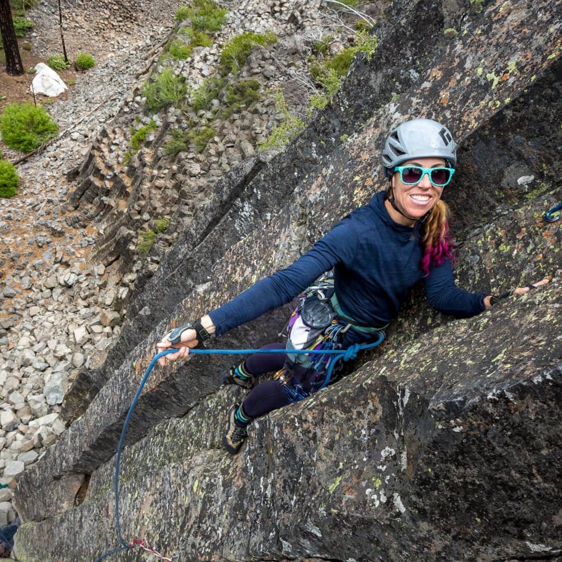 Lindsey Jackson leads a rock climbing pitch wearing an Outerspace Heather Pursuit Hoodie and sunglasses