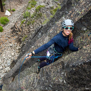Lindsey Jackson leads a rock climbing pitch wearing an Outerspace Heather Pursuit Hoodie and sunglasses