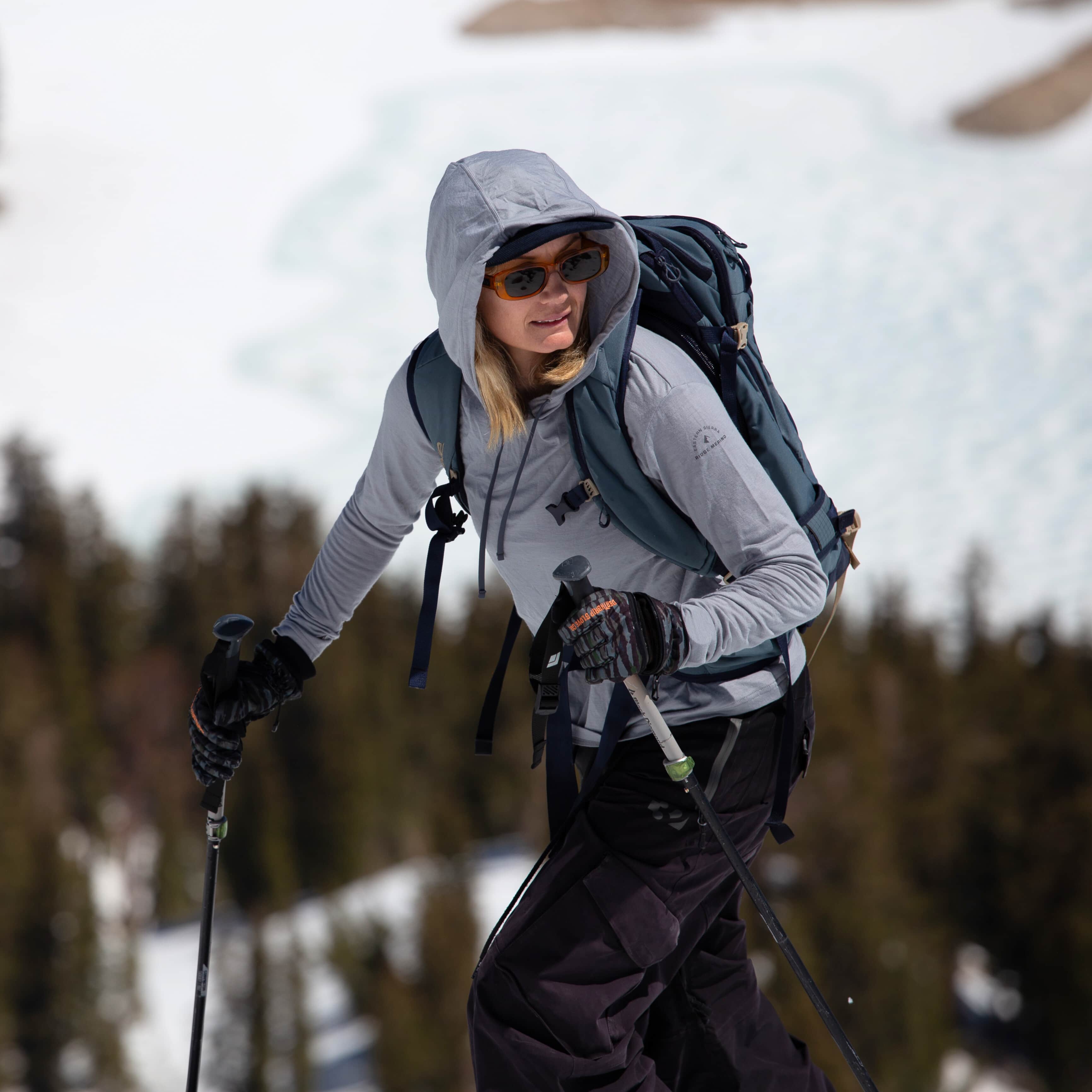a woman on a spring ski tour wearing a Solstice Sun Hoodie in Sierra Cement
