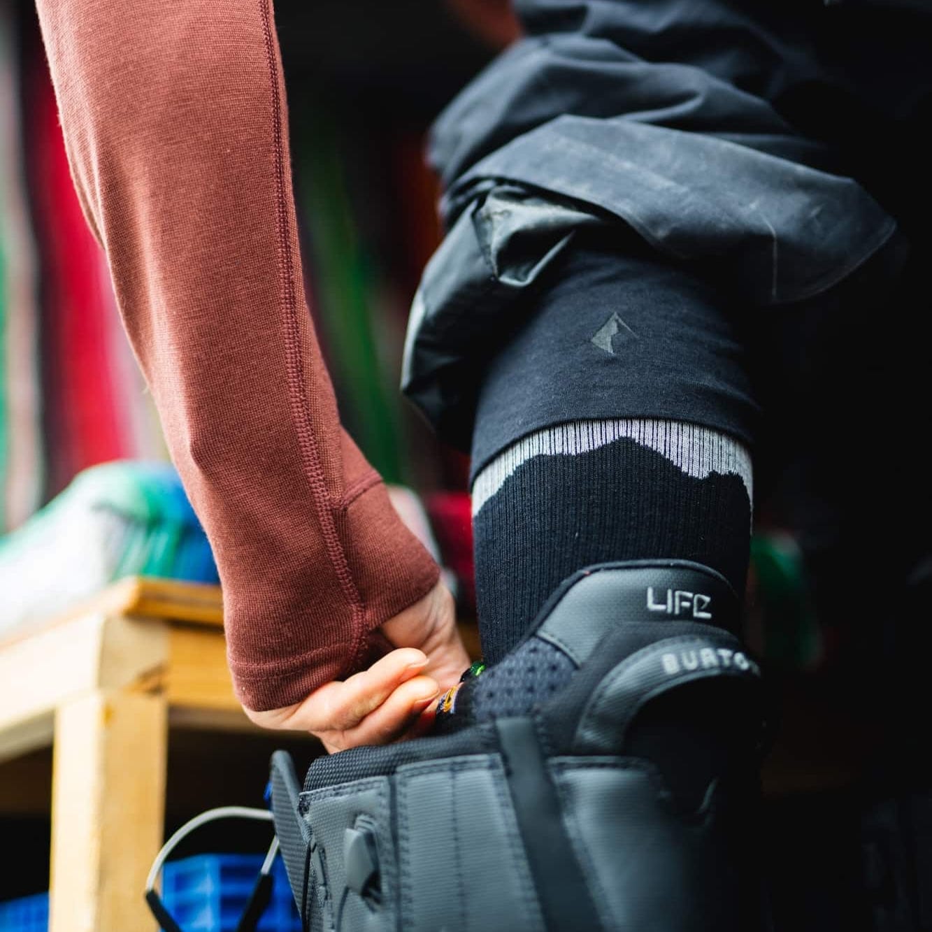 a snowboarder puts on a snowboard boot with Ritter Merino Ski Socks