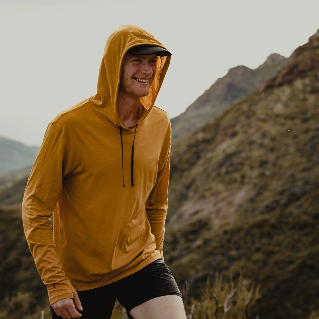 a man wearing the Goldenrod Solstice Lightweight Pullover Sun Hoodie with the hood up