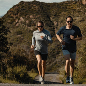 A man and woman running together in Malibu wearing a Pursuit Hoodie and Pursuit Tee