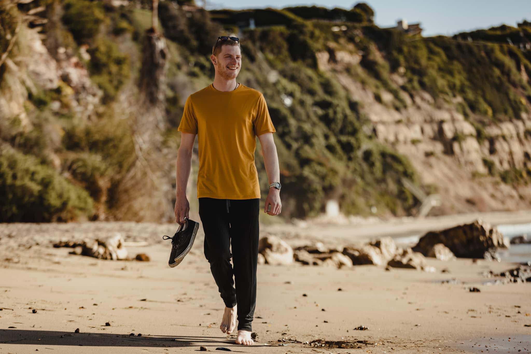 a man walking on a beach wearing Hyde Joggers and a Journey T-shirt
