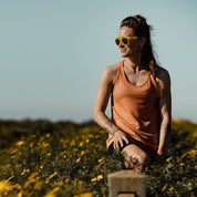 a woman wearing sunglasses and a Frankie Merino Wool Tank Top smiles in a field of flowers