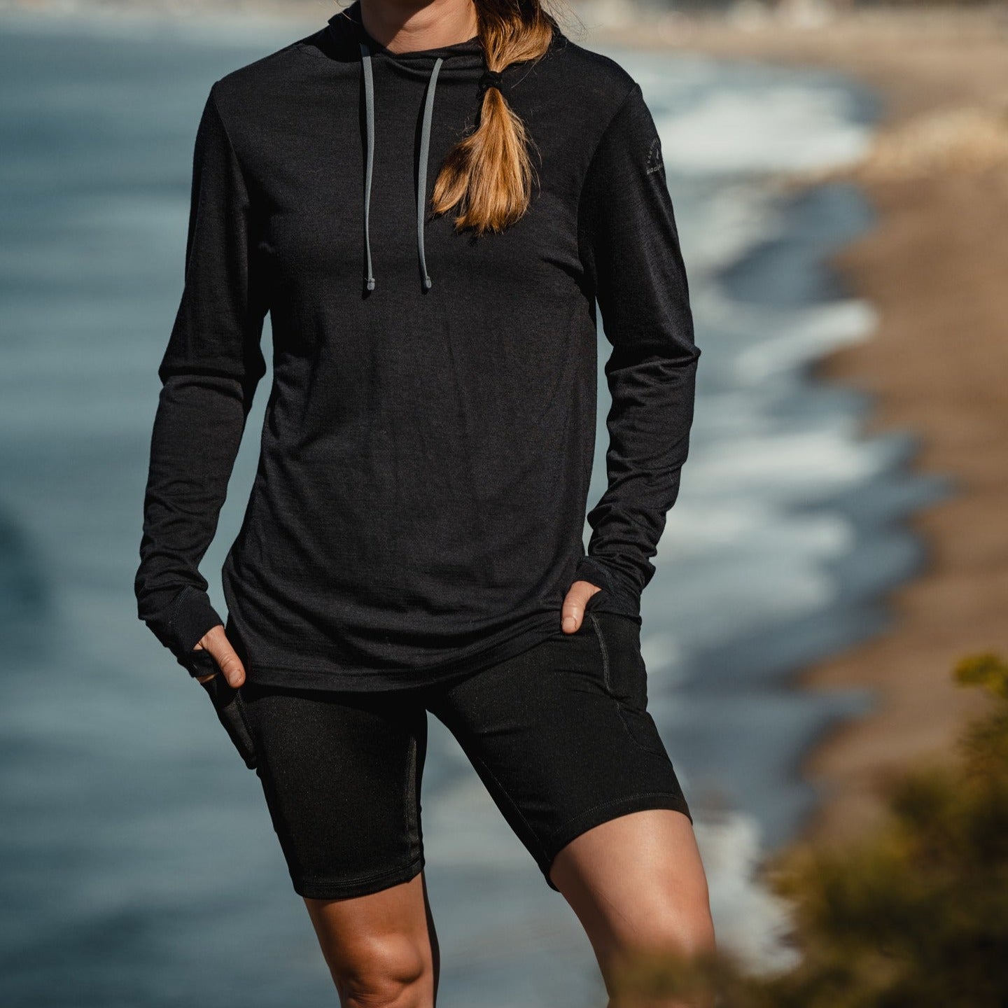 a woman wearing a Solstice Sun Hoodie and Hilltop Merino Wool Shorts