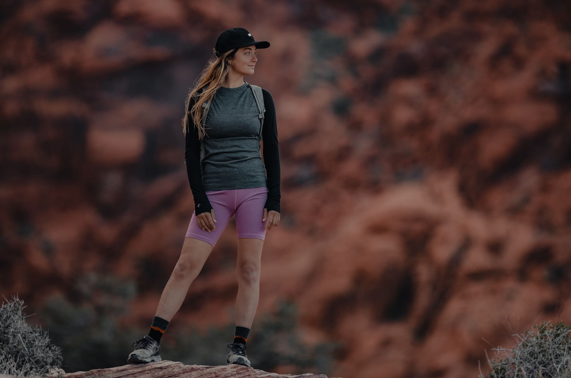 a female hiker standing on a rock wearing a Ridge Merino Aspect Base Layer Shirt and Hilltop Shorts