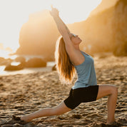 a woman doing yoga on a beach in the Hilltop Bike Shorts and Frankie Tank