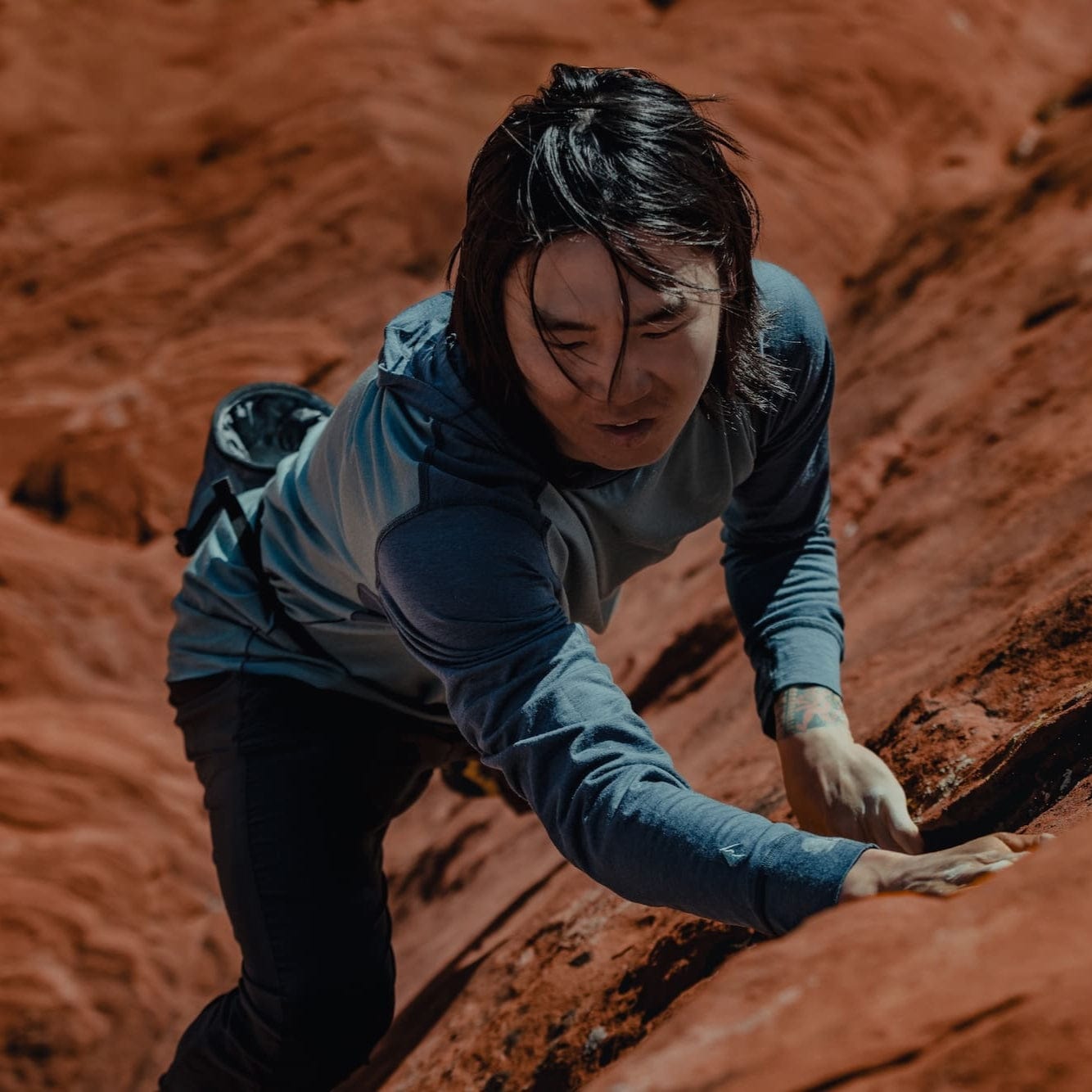 a man bouldering in a Pursuit Hoodie