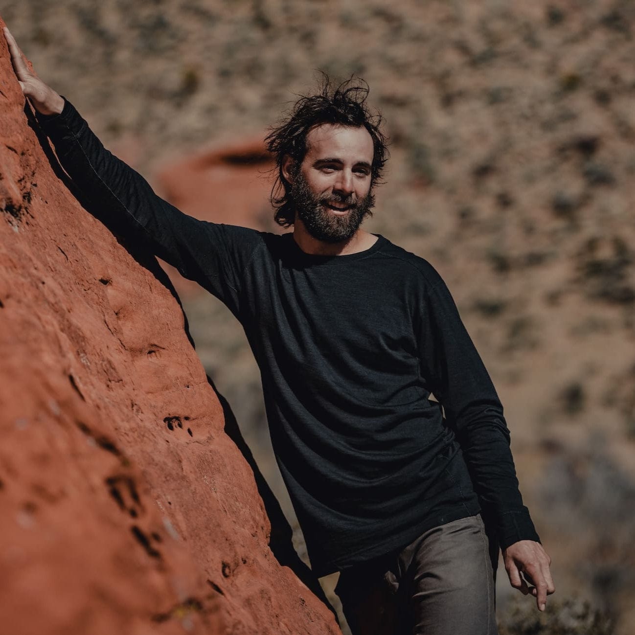 a man casually bouldering in a black Pursuit long sleeve tee