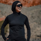 a woman smiles wearing a black Pursuit Ultralight Merino Hoodie