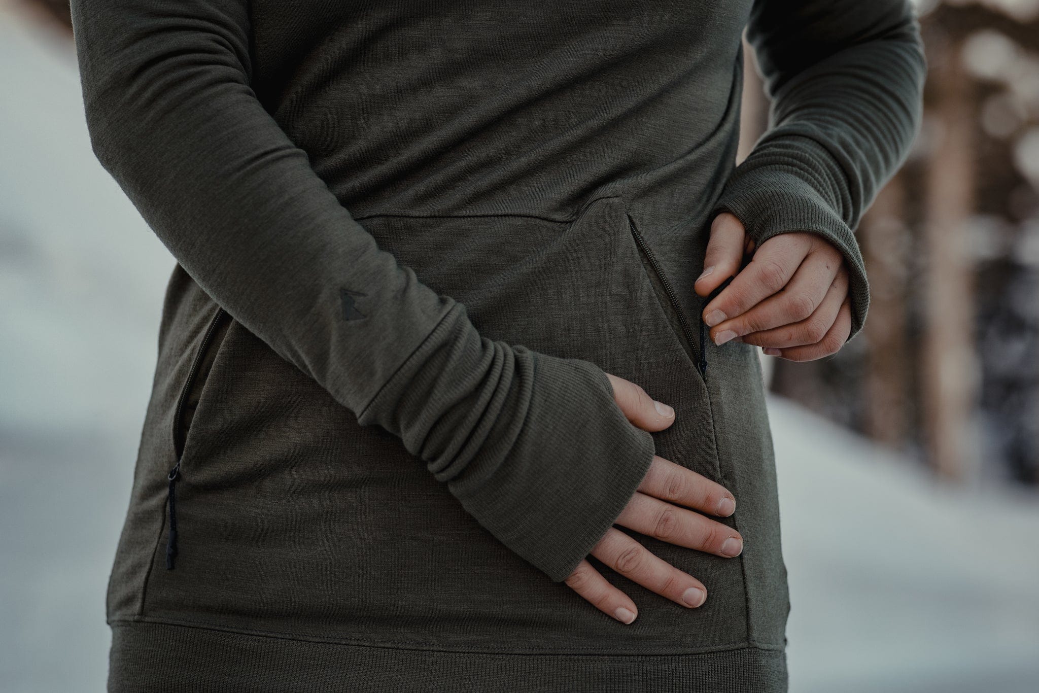 a close up of a woman wearing the Ridge Natural Merino Tencel Hoodie showing the zippered pockets and long sleeves with thumbholes