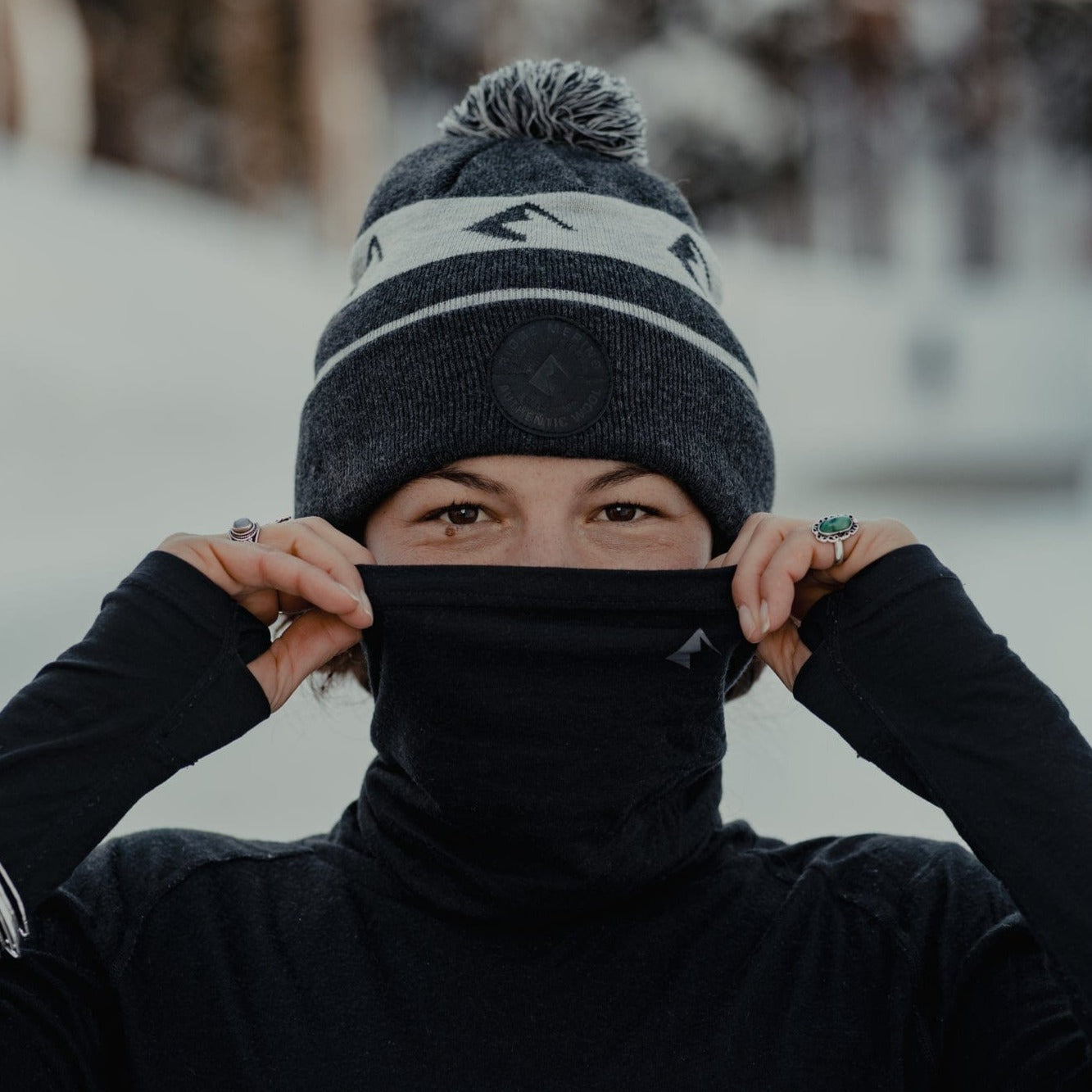 a woman wearing an Aspect high neck base layer top with the face cover pulled up and a Ridge beanie