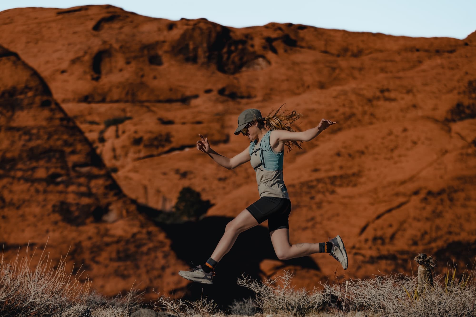 a woman jumps wearing Hilltop Shorts and a Wander Tank Top