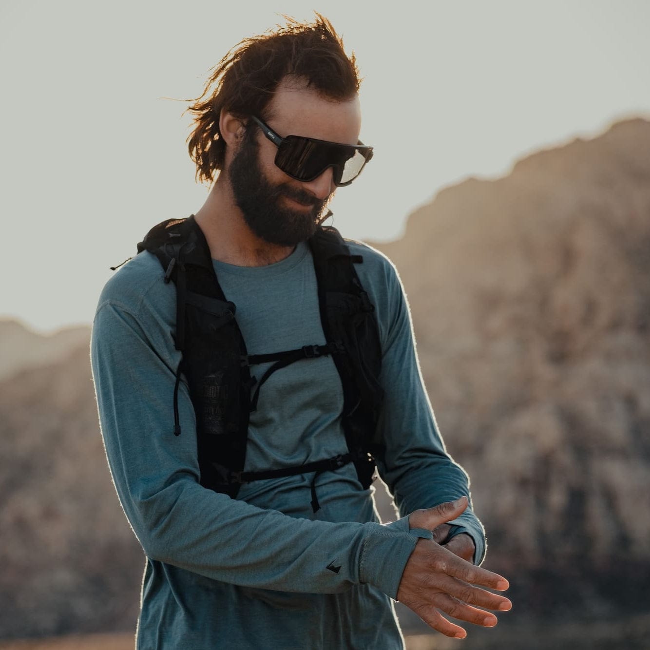 a man preparing for a run in a Pursuit Ultralight Merino Wool Long Sleeve Shirt with thumb holes