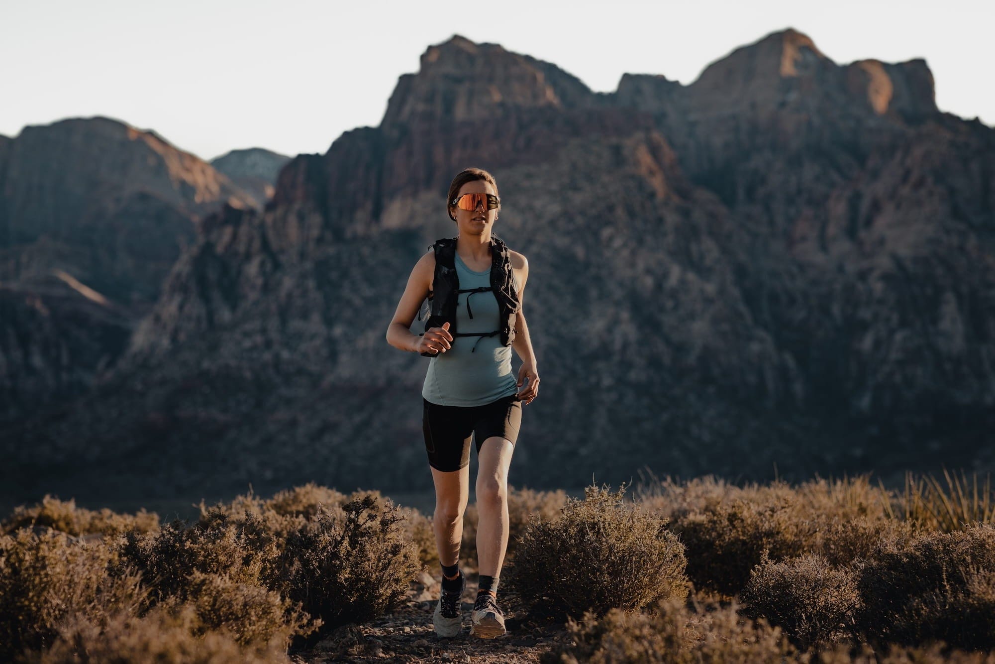 a woman running in a Ridge Merino Racerback Tank and Hilltop Shorts