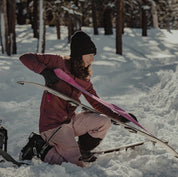a woman putting skins on her splitboard wearing a Hyde Merino Hoodie