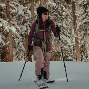 a woman smiles backcountry skiing in the woods