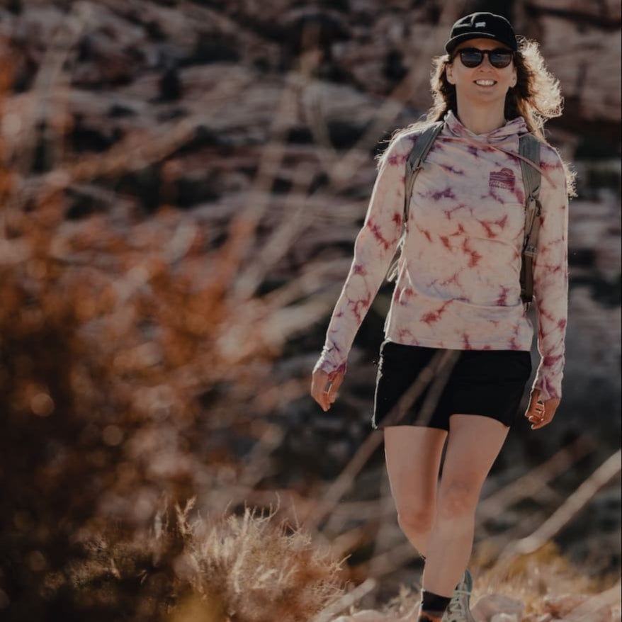 a woman hiking in a tie-dye Solstice Sun Hoodie