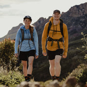 a man and a woman both wearing Solstice Sun Hoodies and backpacks on a hiking trail