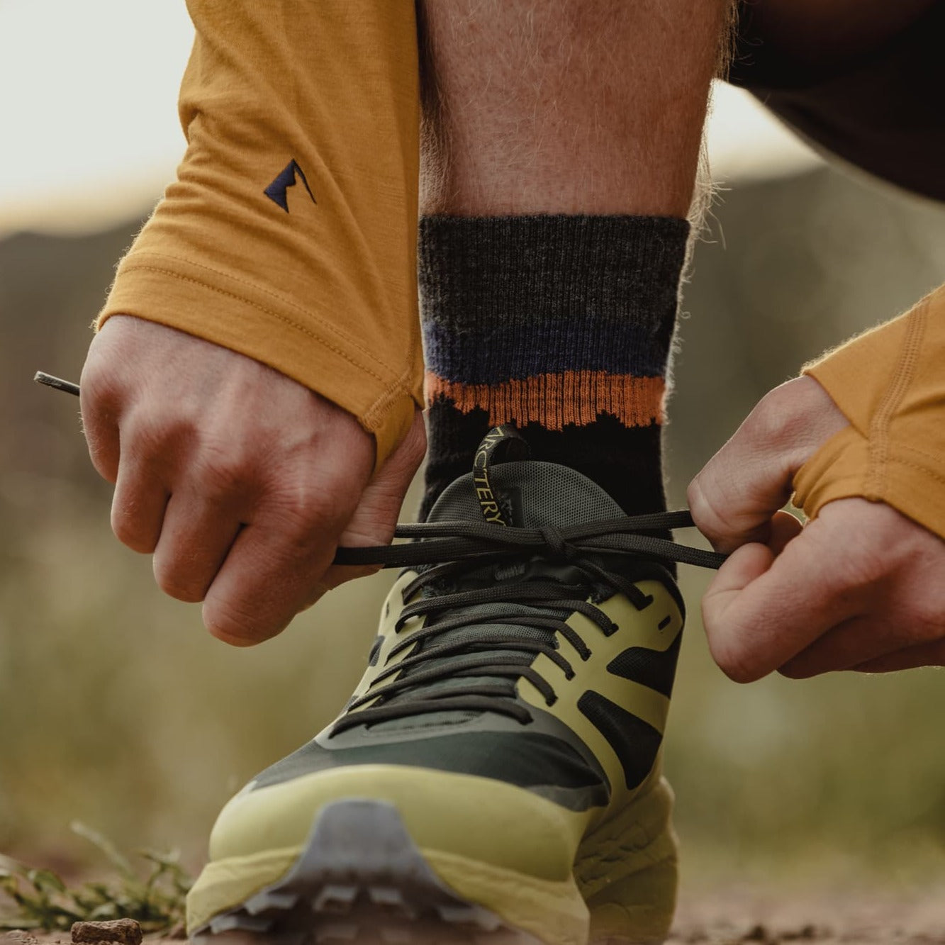 a man ties his running shoe wearing Minaret Hiking Socks