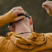 a man wearing a Solstice Sun Hoodie and Ridge Run Merino Hat showing the back tightening cord