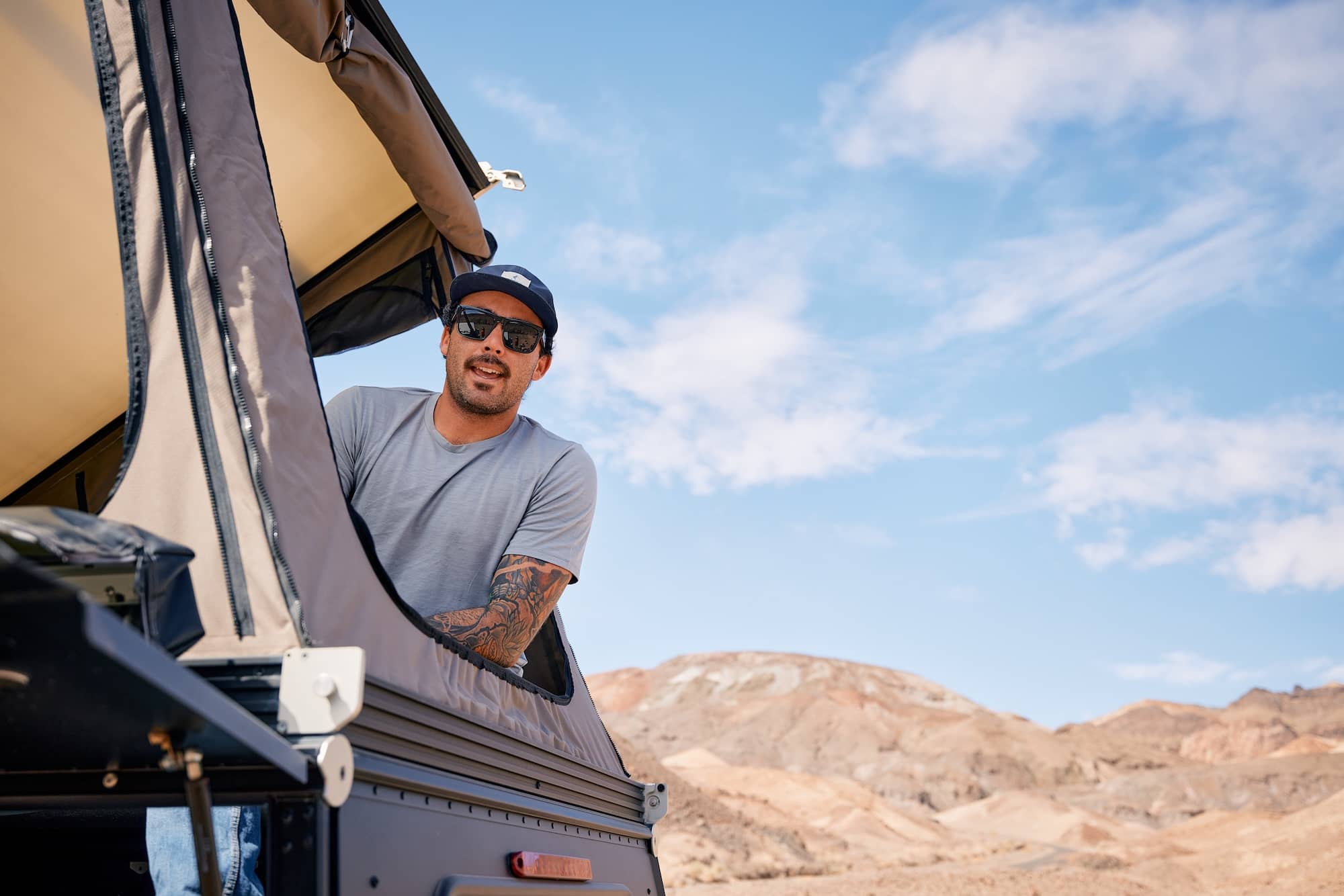 a man leans out of his rooftop tent wearing a Journey Merino T-shirt