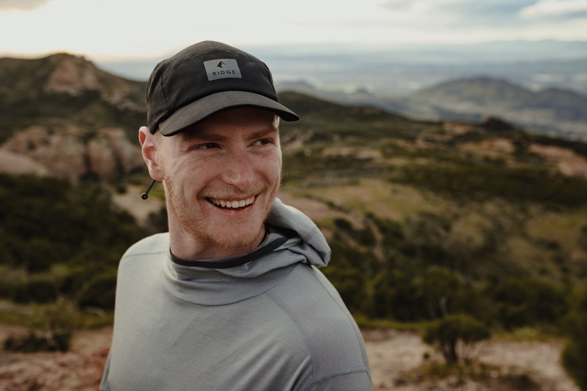 a man wearing a Pursuit Hoodie and Ridge Run Hat on a run
